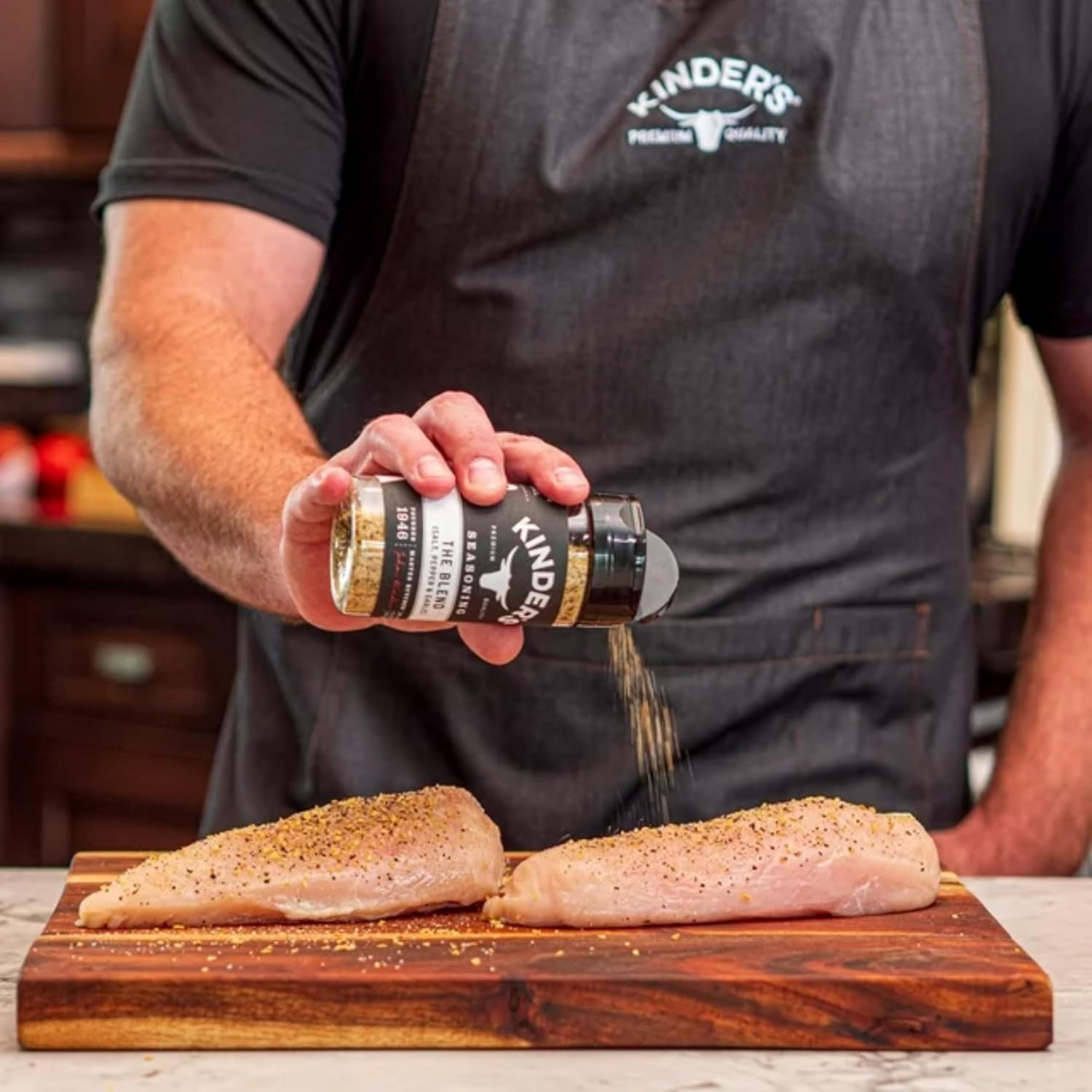 Seasoning sprinkled onto chicken breasts on a cutting board.